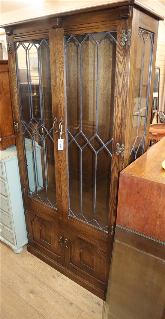 A reproduction oak display cabinet enclosed by leaded glazed doors W.88cm